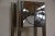 This chrome electric plug in clock has four cylindrical posts with two glass shelves and a black simple modern face. 16”...