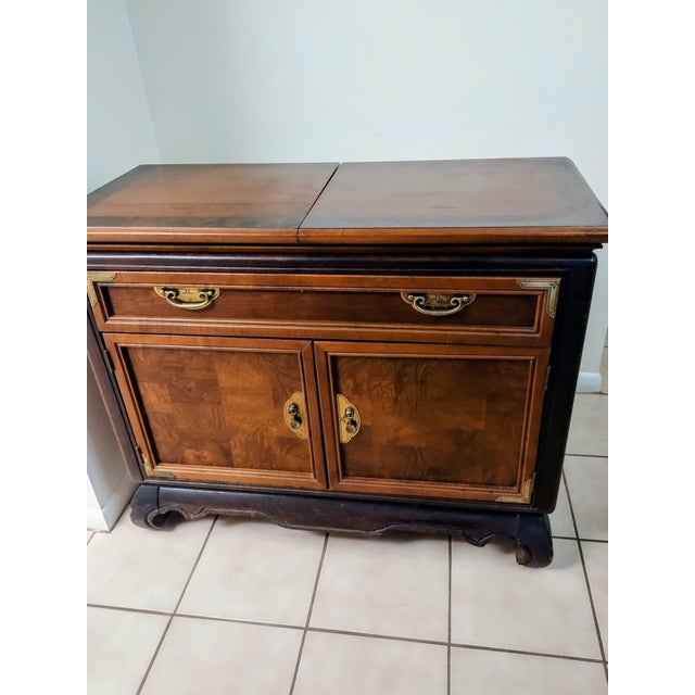 This cabinet, featuring an extendable table and a wine rack, is crafted from solid wood and adorned with bronze details....