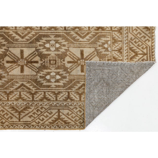 Elevate luxury interiors with this exceptional vintage hand-knotted wool runner rug. Featuring a refined palette of warm...