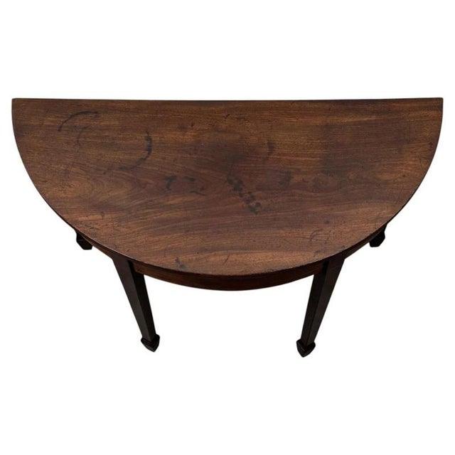 A beautifully proportioned 19th-century demi-lune side table in mahogany, displaying the refined elegance and restrained...