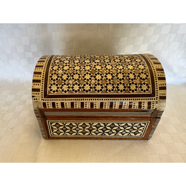 This domed box is inlaid with bone, mother of pearl, rosewood and ebony. It is lined with red velvet. The box is...