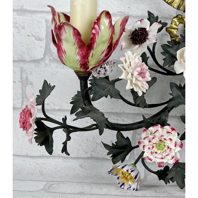 A two-light wall sconce in wrought iron and cut sheet metal, executed in the naturalistic style. Its gracefully sinuous...