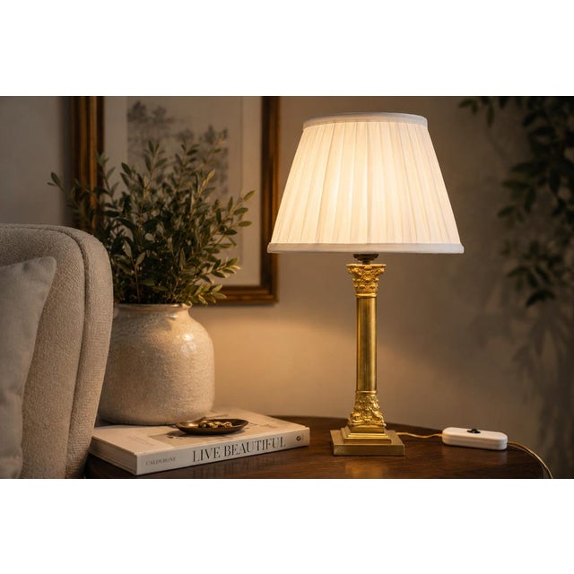 An elegantly proportioned brass table lamp in the classical column form, combining a tall cylindrical stem with richly...