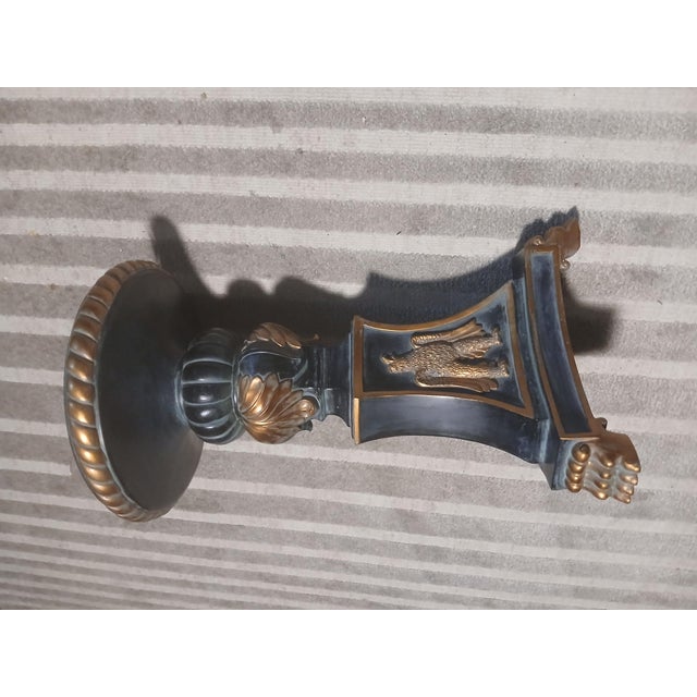 Elegant Hollywood Regency–style side table featuring a round glass top set over an ornate pedestal base. The sculptural...