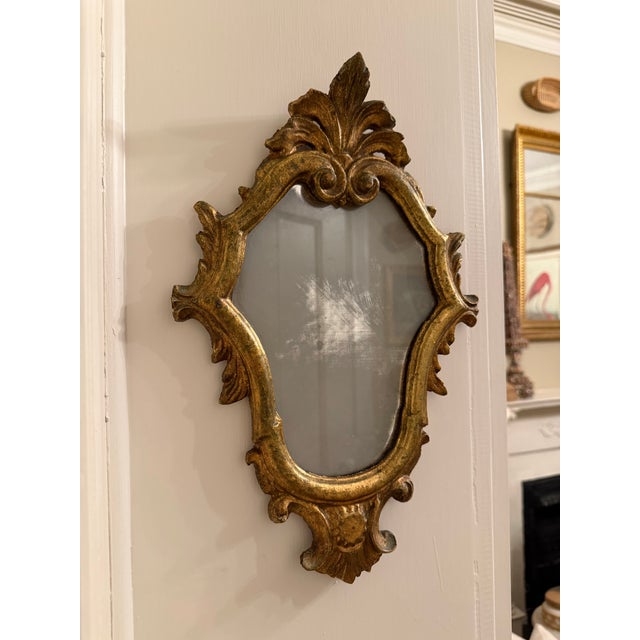 This is a beautiful vintage Italian Florentine-style giltwood mirror, featuring an ornate carved frame with a graceful,...