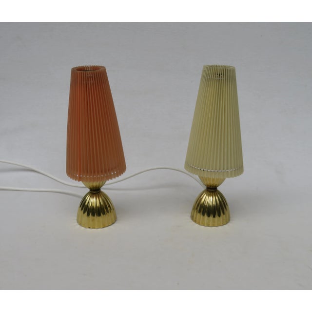 1 pair of small table lamps from the 50s with pleated plastic shades and brass base. Interesting about these two lamps is...