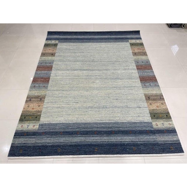 This gray wool rug features a hand knotted pile construction in the traditional Gabbeh style. Produced in India, it...