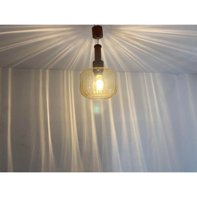Vintage pendant light from former Yugoslavia, dating from the 1970s. The design combines a warm amber-colored textured...