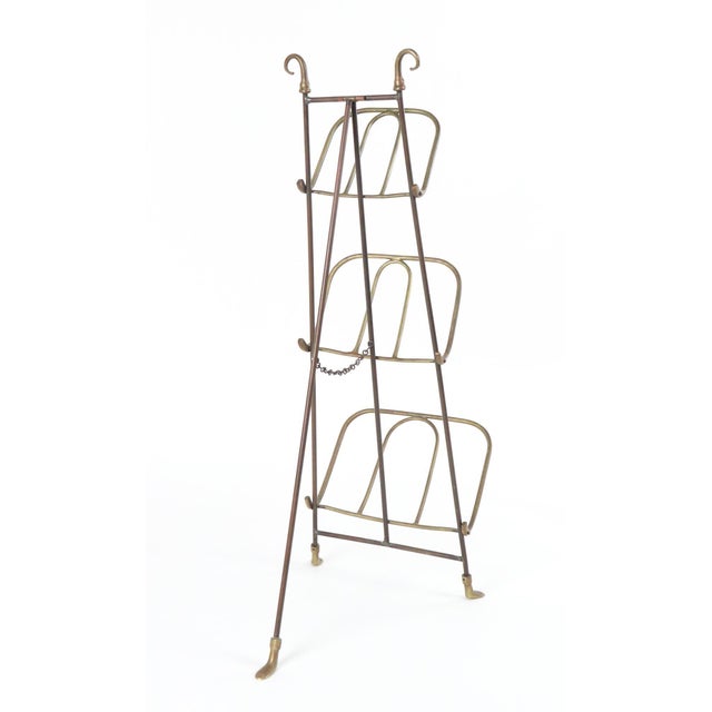 Early 20th century brass three-tiered rack, designed to hold magazines or newspapers. Tripod design with fold-out back...