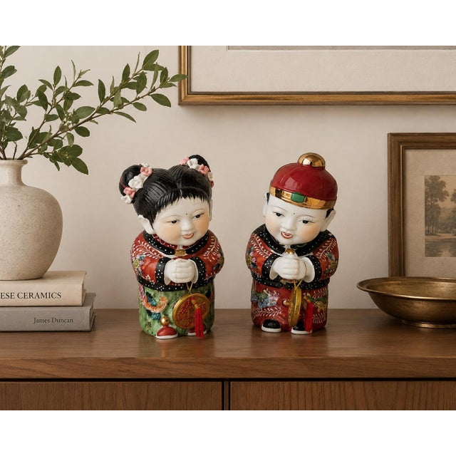 Charming vintage pair of hand-painted Chinese porcelain figurines depicting a traditional boy and girl dressed in richly...