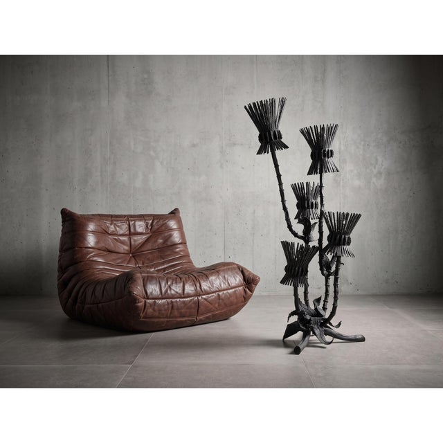 This floor lamp reflects the Brutalist movement of the 1970s, crafted from wrought iron and metal with a matte black...