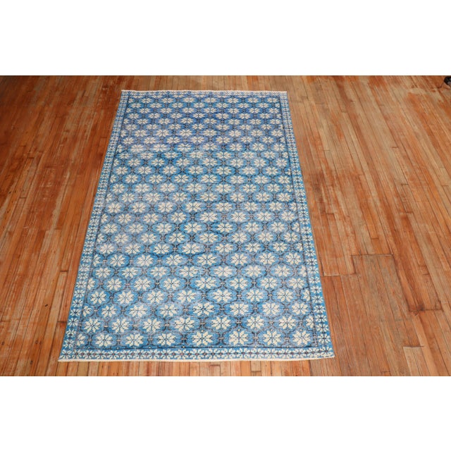 A Mid-20th worn Century Turkish Deco intermediate rug featuring a repetitive all-over design on a vivid blue ground...