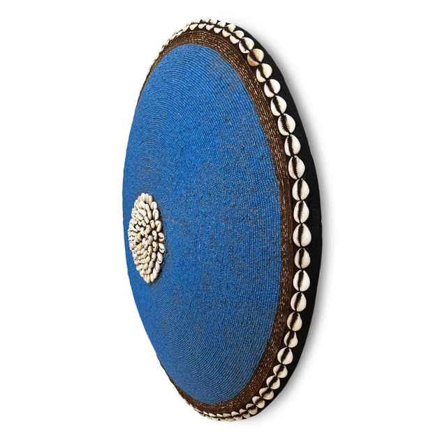 Striking blue hand beaded shield with cowry shell border and center. Wooden shield as base. Makes for beautiful unique...