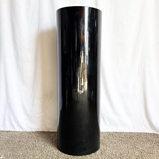 A striking postmodern pedestal defined by its pure cylindrical form and deep black high-gloss lacquer finish. The...