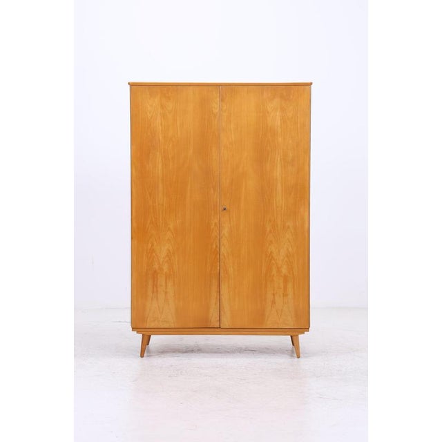 Vintage wardrobe with clean, straight lines and a classic tapered base. The interior is well-organized with several...