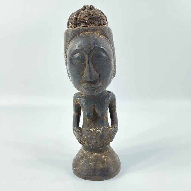 Hand-carved wood Kusu female figure with distinct body markings and influence from their Songye and Hemba neighbors. This...
