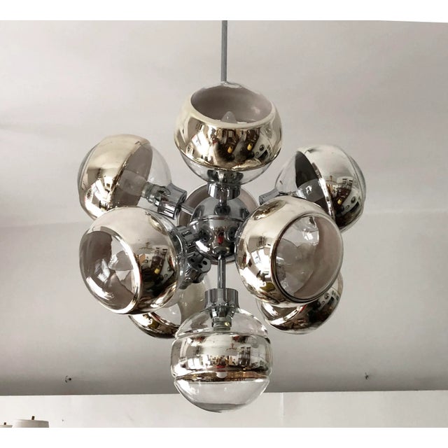 This piece features a chrome-plated brass frame with nine glass shades, each of which has a mirror strip fitted with E14...