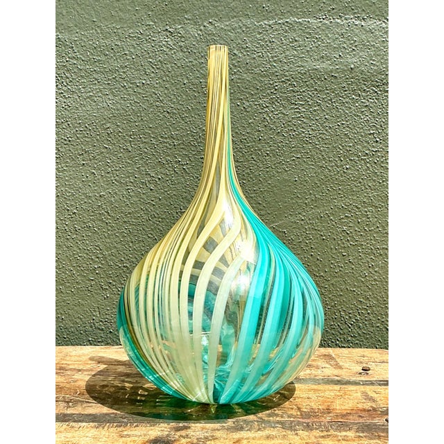 This vintage blown glass vase channels the swirling elegance of Murano-style artistry, its form tapering gracefully from a...