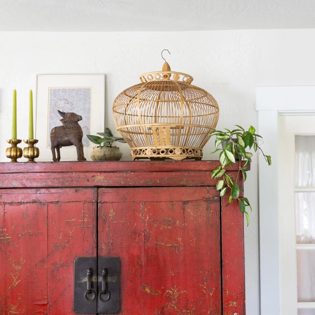 Indonesian bamboo and rattan birdcage features hand-carved rosettes and delicate scrolls at the base and crown, a zig-zag...