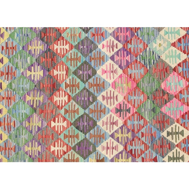 This vintage Afghan Maimana Kilim, measuring 6'7" by 9'11", is handwoven with wool on a wool foundation by the Maimana...