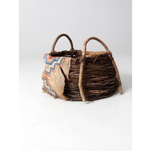 Antique painted bark basket featuring a hand-woven twig construction and rustic bentwood double handles. The form is...