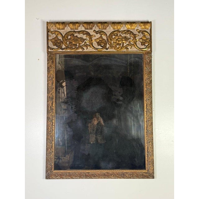 An elegant 19th-century Italian mirror featuring a finely carved and painted wood frame with richly aged parcel gilding....