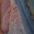 This artwork features a poised figure draped in a delicate, embroidered shawl, standing against a backdrop of flowing...
