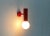2 plain Mid Century wall sconces in a very simple design language. A red cylinder, at the end of which sits the socket for...