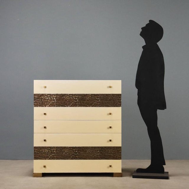 1970s dresser in white lacquered wood, featuring an elegant worked brass front that adds a distinctive touch. The solid...