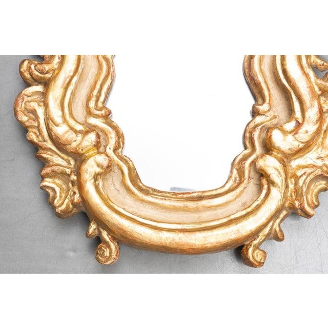 This is a charming Italian Rococo-style wall mirror featuring a richly carved and hand-applied gold leaf frame with...