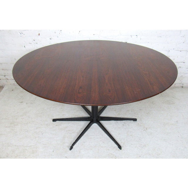 Mid-Century Modern round rosewood dining table with black metal star base. Table not marked.