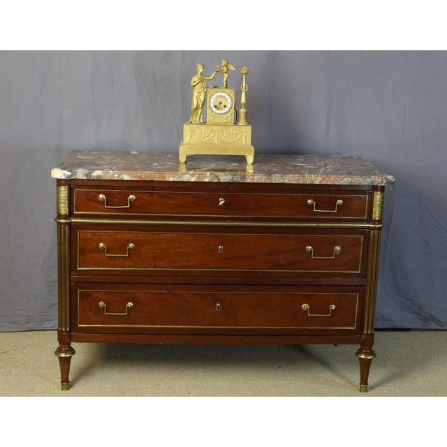 Three-drawer commode with a marble top. This Louis XVI commode from the late 18th century is adorned with brass moldings...
