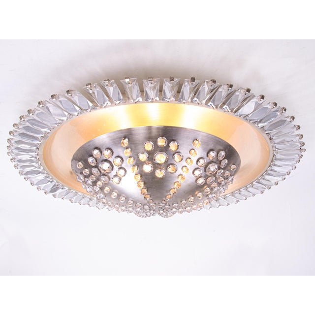 Large, elegant, flush mount chandelier with a nickel metal center body that is pierced with crystals rosettes. The body is...