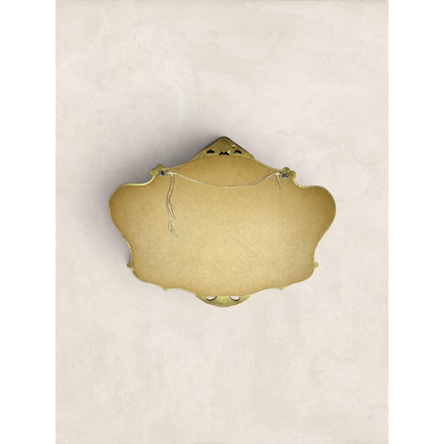 An elegant vintage English gilt wall mirror dating to circa 1980. Featuring a gracefully shaped frame with scrolling...