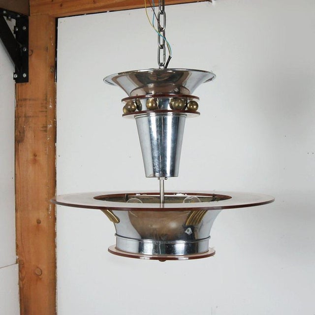 An Art Deco chromed metal and peach glass ceiling light by Petitot. Upper glass section divided by brass roundels above a...