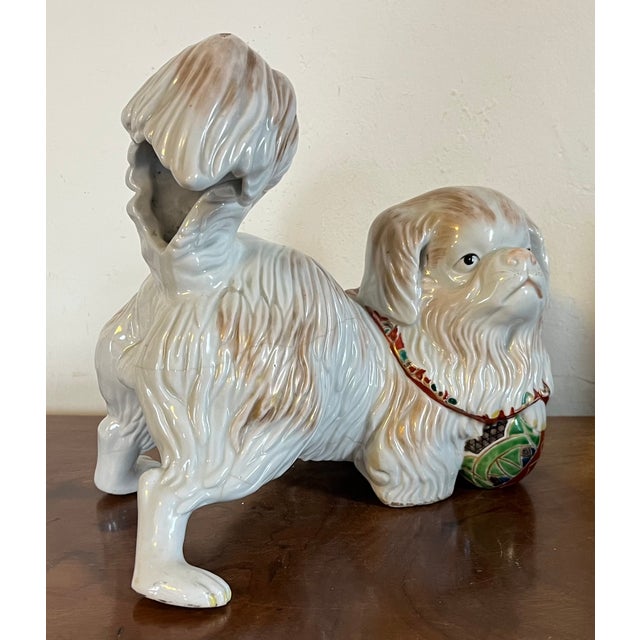 Antique 19th century Japanese Edo Period porcelain okimono in the form of a Pekingese dog. The dog wears a bright red...