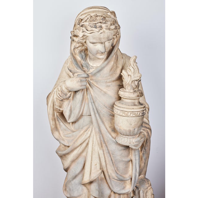 A beautifully sculpted terracotta statue depicting Winter. The robed figure is holding a burning cauldron of fire. A...