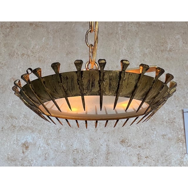 This amazing Spanish 1960s brutalist gilt metal ceiling fixture features a curved circular frame with evenly spaced nails...