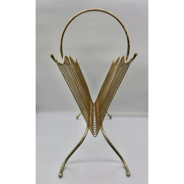 This 1960s brass-tone wire magazine rack features a deep V-shaped cradle of fanned rods, softly scalloped top rails, and a...