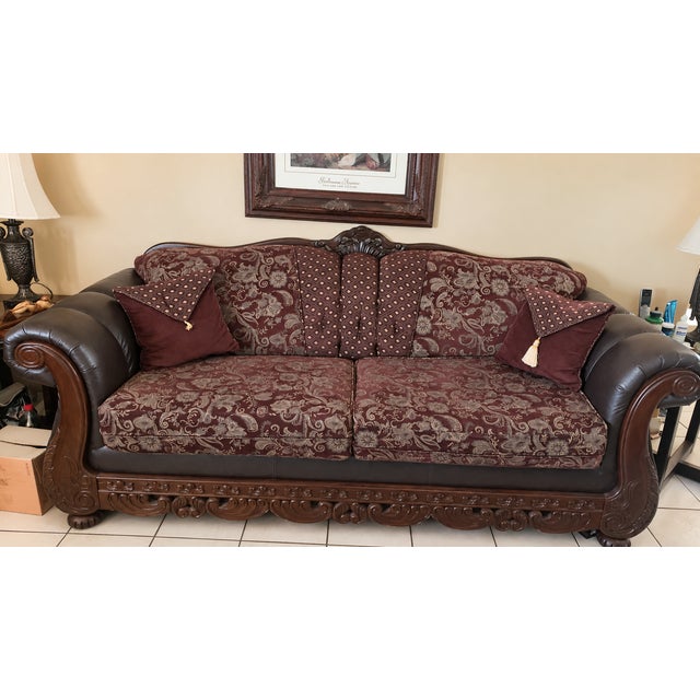 Beautiful traditional two-piece living room set featuring a full-size sofa and matching loveseat with ornate carved wood...