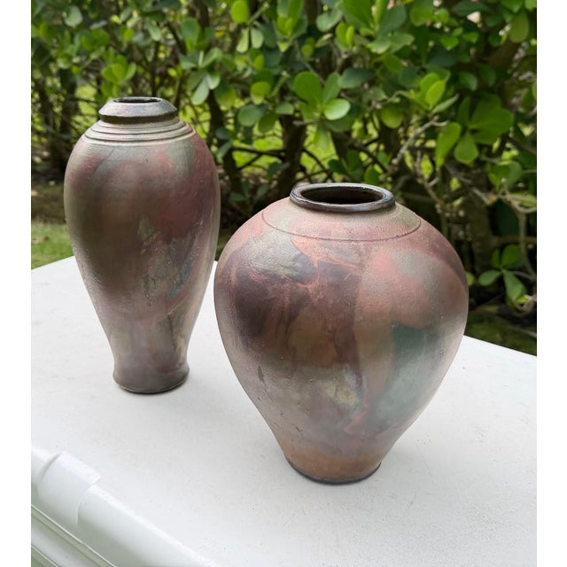 A striking pair of vintage raku pottery vessels featuring complementary forms and richly variegated metallic glazes. The...