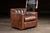 Handsome leather club chair paired with a matching ottoman, upholstered in full-grain brown leather with a soft, supple...