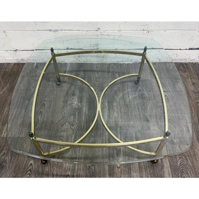 This is a stunning vintage Hollywood Regency brass coffee table with a thick beveled glass top. Features an elegant brass...