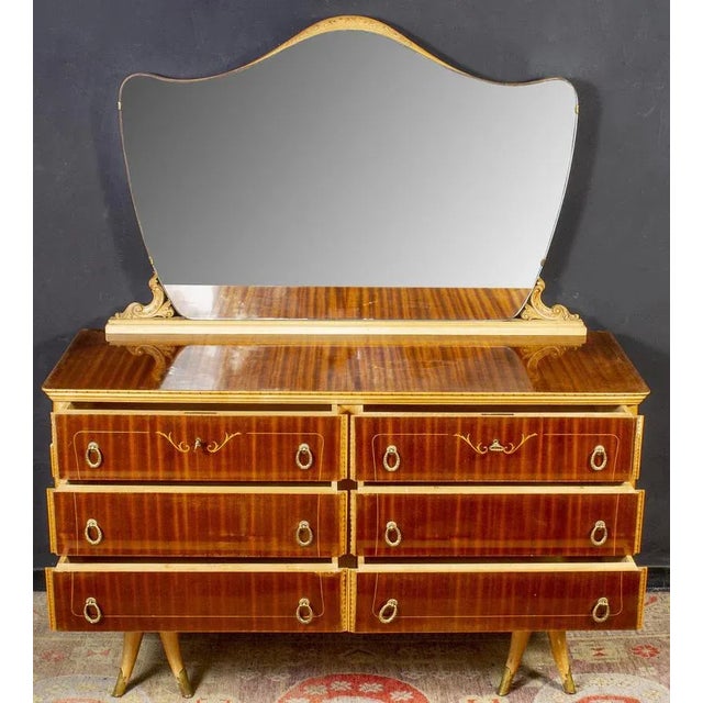 In birch and mahogany veneered with six drawers and brass handles. Available also the finely carved mirror. Measures:...