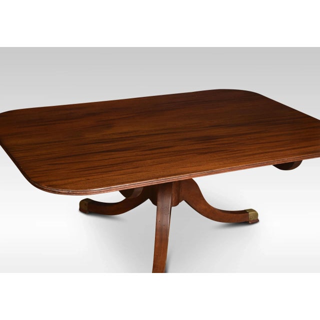 Regency mahogany coffee table, the shaped rectangular top having molded edge raised on a pedestal base and splayed legs....