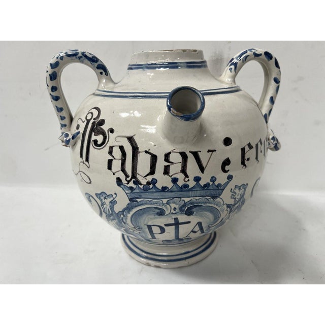 Vase with handles, decorated in white and blue. Crowned cartouche on the front, held by two wolves. Latin inscription....