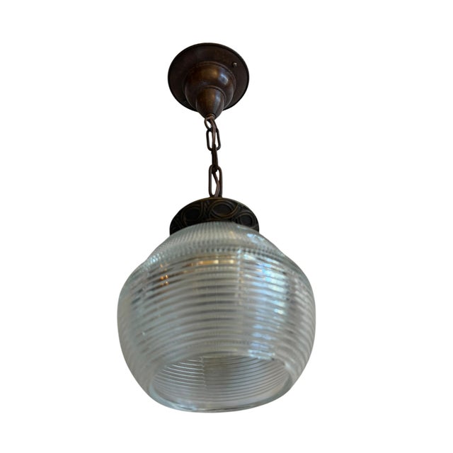 A rare pair of vintage pendant lights featuring prismatic and ribbed glass shades and ornate bronze-toned brass fitters...