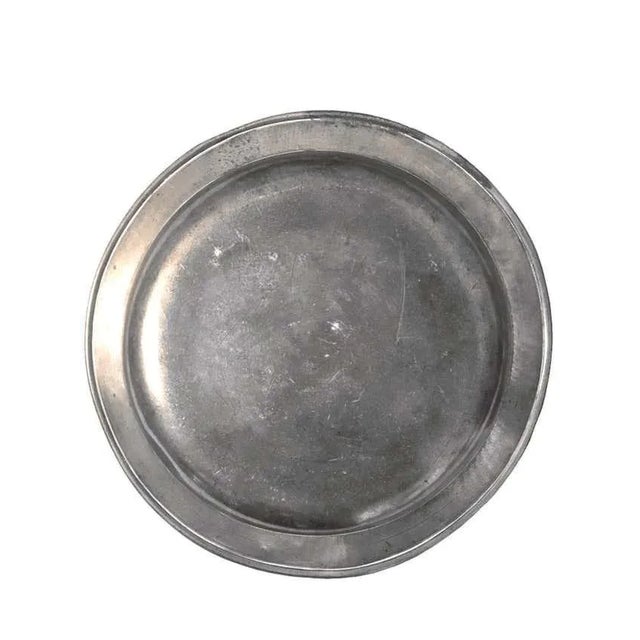 Pewter deep dish with crowned coat of arms with fleur de lys and Chevrons in the center. The crown topped by a cross is...