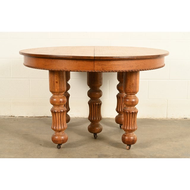 An outstanding antique Victorian or American Empire carved oak extension dining table In the manner of R.J. Horner & Co....
