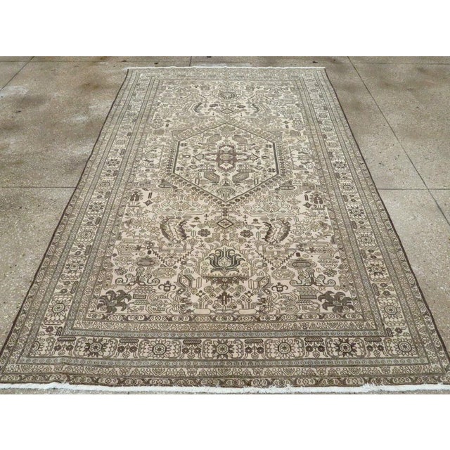 This mid-20th-century Persian Tabriz accent carpet presents an intricate geometric-floral composition across a warm ivory...